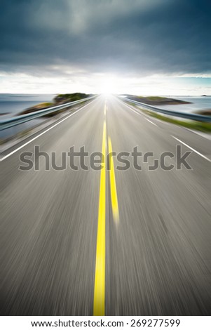 Scenic view of coastal highway or road receding on coastline with slow motion blur and sunny background.
