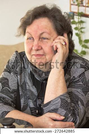 Happy elderly woman talking on the phone.At home in the kitchen.