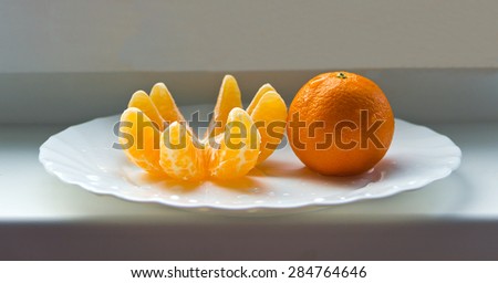 The mandarin and the mandarin slices on the plate.