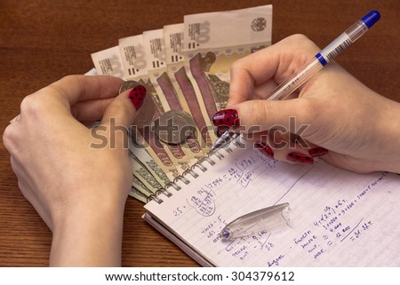 Woman's hand-writes the expenses in a notebook.