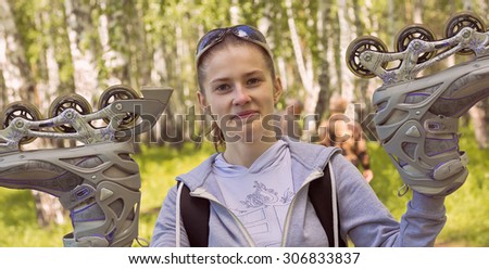 Sports girl with sunglasses raises roller skates up.