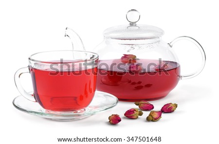 Fresh brewed rose tea in a glass teapot and a cup and a few buds of a tea rose isolated on white background.