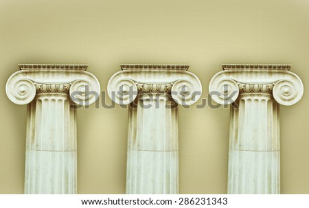 Three antique columns in doric style on a beige background