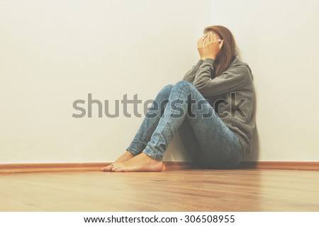 Sad girl hiding in corner at home