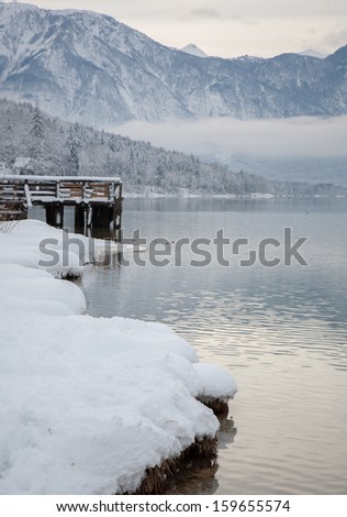 landscape of the lake bohinj and wooden dock in winter with bad weather, slovenia