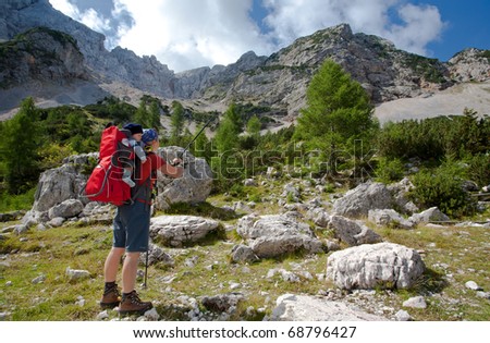 mother with baby carrier carrying a son in alps on a sunny day