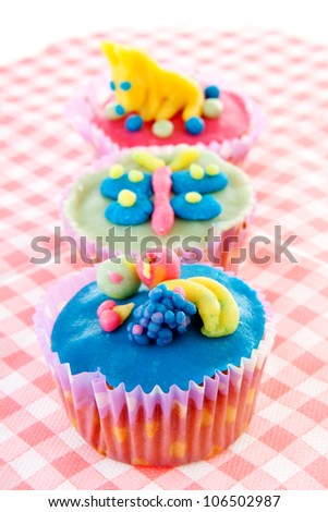 three cupcakes with marzipan decoration on napkin