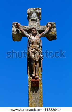 Statue of Jesus on a stone cross over blue background