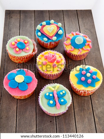 Couple of cupcakes with marzipan decoration on wooden background