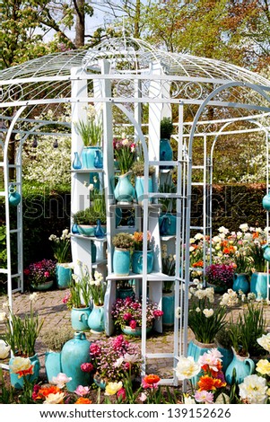 Garden house arbor with lots of blue pots and colorful flowers on sunny day
