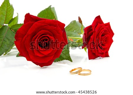 stock photo Two red roses and wedding rings over white background