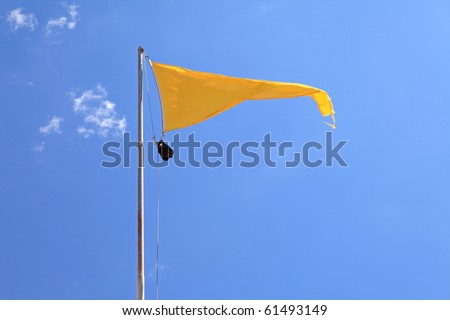 yellow warning flag on the beach against blue sky