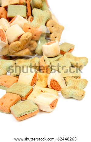Pile of dog cookies falling out of bag over white background