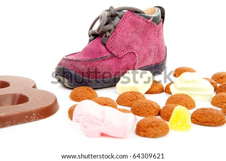 purple little children\'s shoe with chocolate letter and pepernoten ( ginger nuts), traditional for Sinterklaas in the Netherlands over white background