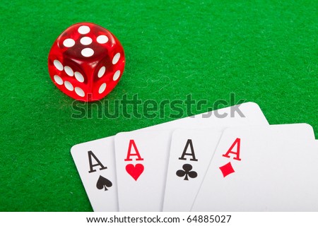 winning poker hand of four aces playing cards and red dice on green background