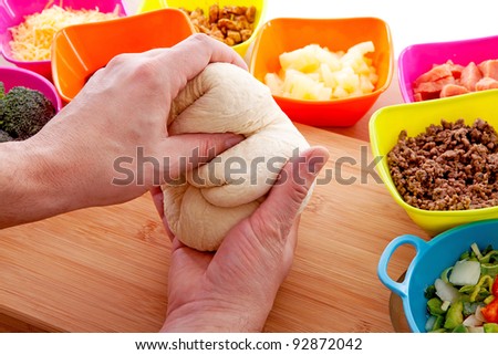 Making pizza: ingredients and hands with pasta dough on wooden cutting board