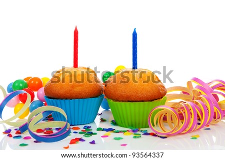 Birthday cupcakes with lots of candles, party streamers and colorful confetti over white background