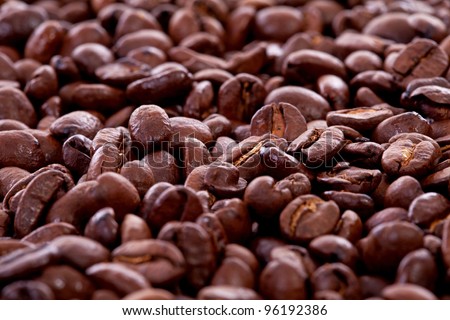 Cup in pile of roasted beans and regular ground coffee over white background