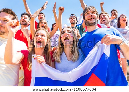 Russian supporters celebrating at stadium with flags. Group of fans watching a match and cheering team Russia. Sport and lifestyle concepts.