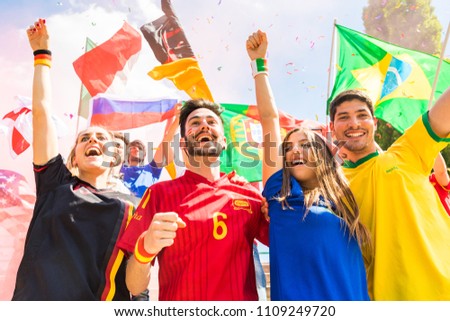 Happy supporters from different countries together at stadium. Fans from France, Germany, Spain, Brazil and other countries enjoying a match together. Sport, achievement and success concepts