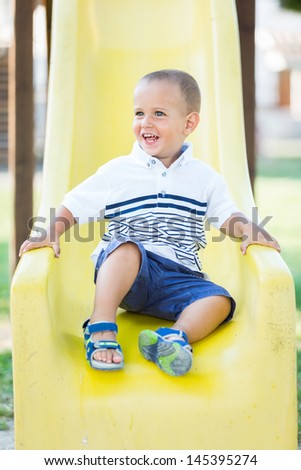 Little Boy Playing on the Slide at Park