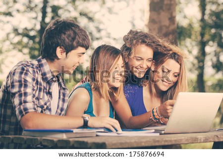 Group Of Teenage Students At Park With Computer And Books