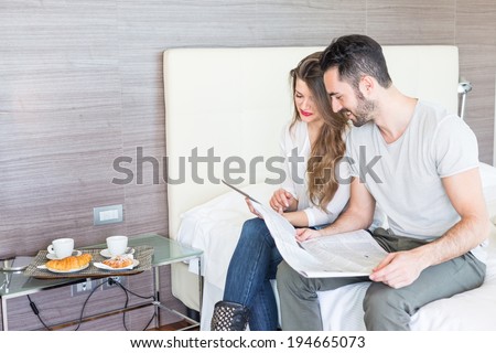 Couple with Digital Tablet and Newspaper