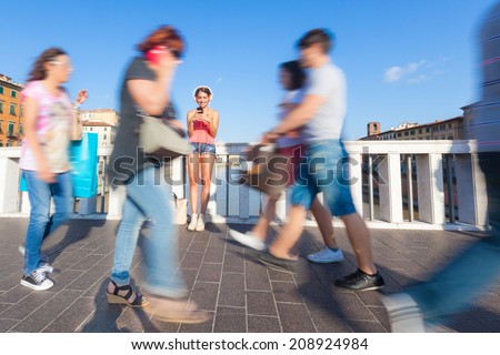 Beautiful Girl typing on Mobile Phone with Blurred People Walking