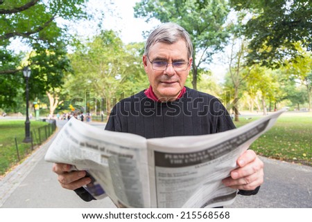 Senior Man Reading Newspaper at Park