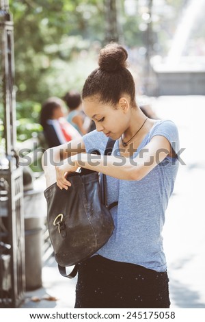 Beautiful Mixed-Race Young Woman Looking Inside Her Bag