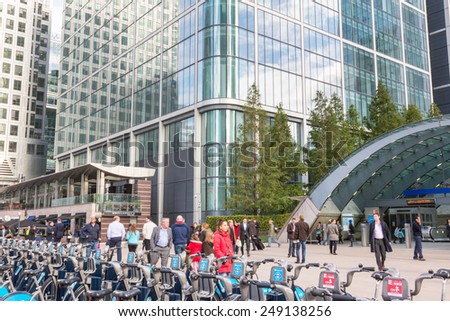 LONDON, UNITED KINGDOM - OCTOBER 30, 2013: Canary Wharf district with Barclays Cycle Hire docking station and Underground entrance. Many people, tourists and commuters, are walking in the square.