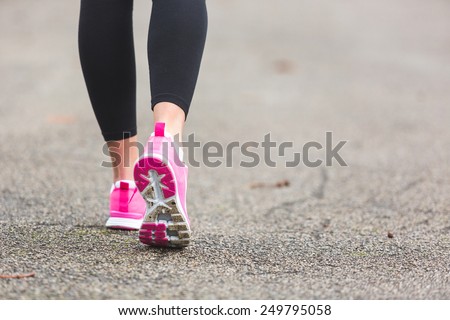 Female Runner Shoes closeup on the road, town setting. Shallow depth of Field, focus on rear shoe.