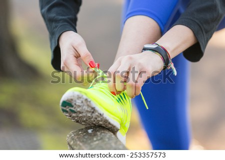 Young Sporty Woman Doing Up her Shoes Before Running. Close Up Shot of her Hands. She wears Glow Yellow Shoes.