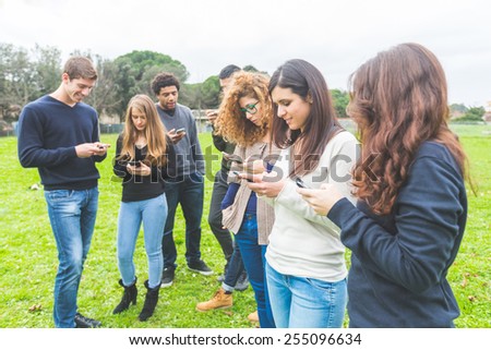 Multiethnic group of friends looking at their own smart phone. Technology, internet and social network addicion concepts, modern social issues.