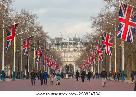 LONDON, UNITED KINGDOM - MARCH 8, 2015: The Mall road with many big United Kingdom flags, also known as Union Jack. Some tourists are walking on the street.
