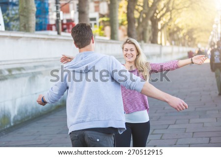 Happy young couple meeting after long time, running into each other with open arms and smiling