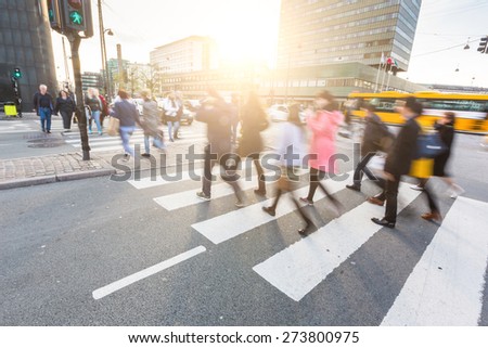 Blurred crowd of people walking on zebra crossing in Copenhagen in late afternoon. Some of them also bring a bike, typical mode of transport in the city. Unrecognizable faces.
