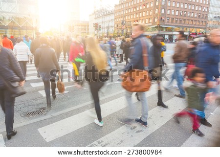 Blurred crowd of people walking on zebra crossing in Copenhagen in late afternoon. Some of them also bring a bike, typical mode of transport in the city. Unrecognizable faces.