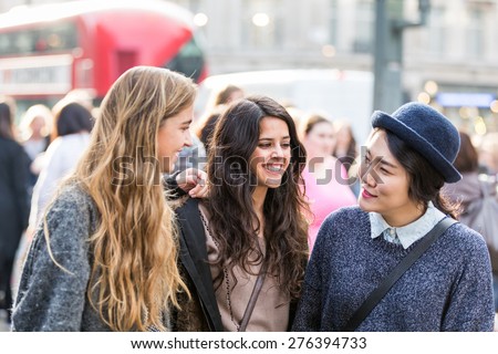 Multiracial group of girls walking in London. Urban background with busy road and sidewalk, friendship and lifestyle concepts.Group consists of one girl from Korea, one from Spain and one from Holland