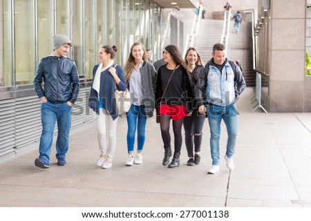 Group of friends walking and having fun together in London. They are four girls and two boys in their twenties, friendship and lifestyle concepts, autumn clothing