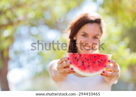 Beautiful young woman showing a slice of watermelon as a smile. She is caucasian, she wear a white dress and she has a braid on the shoulder. Summer and lifestyle concepts.