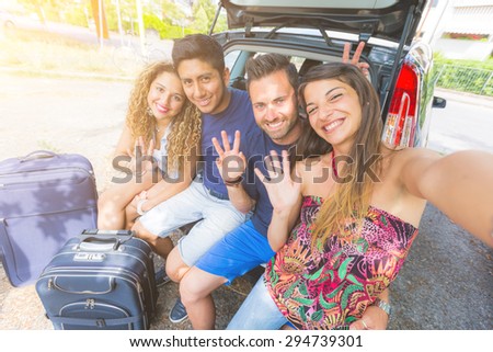 Group of friends taking a selfie in the back of the car before leaving for vacations. They are a mixed race group of four persons, two caucasian and two hispanic.