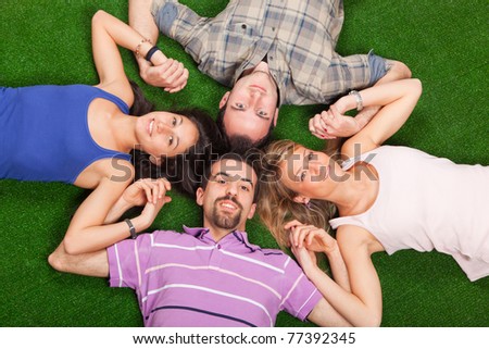 Young People Lying on Green Ground with Hands Joined