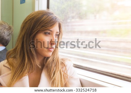 Beautiful young woman looking out of train window. She is on her mid twenties, mixed race face, she seems to be pensive and sad. There is a free space on right to add some text. Travel concept