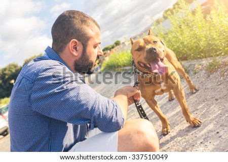 Man with his dog at park. He is looking at his dog standing with open mouth. The main subject is the dog. Concept of friendship between dogs and humans.