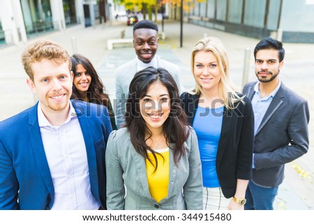 Business group looking at camera. They all are young, smiling and wearing smart casual clothes. Mixed race group, three women and three men. Teamwork and business concepts.