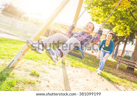 Young boy having fun on the swing. His mother or babysitter his swinging him and they are both enjoying it. Happy family and childhood lifestyle.