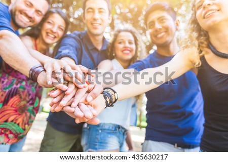 Multiracial group of friends with hands on stack. They are six persons, three boys and three girls, on their early twenties. Teamwork and cooperation concepts.