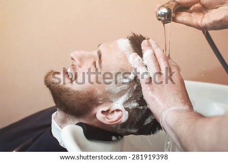 Young man having his hair washed in a hairdressing salon after hair cutting.
