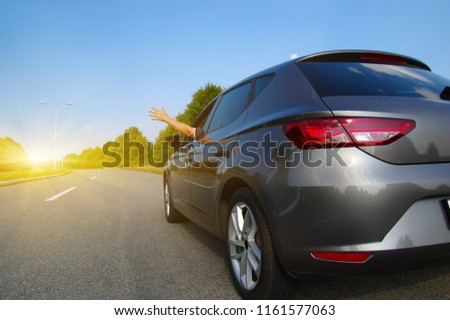 Car on asphalt road in nature. Man hand relaxing and enjoying road trip and sunny.